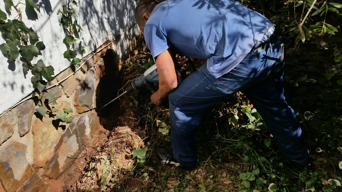 A technician drilling along a house foundation for a termite treatment