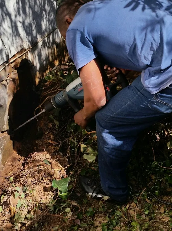 A technician drilling along a foundation for a termite treatment